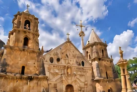 Stone church facade with bell towers under a blue sky